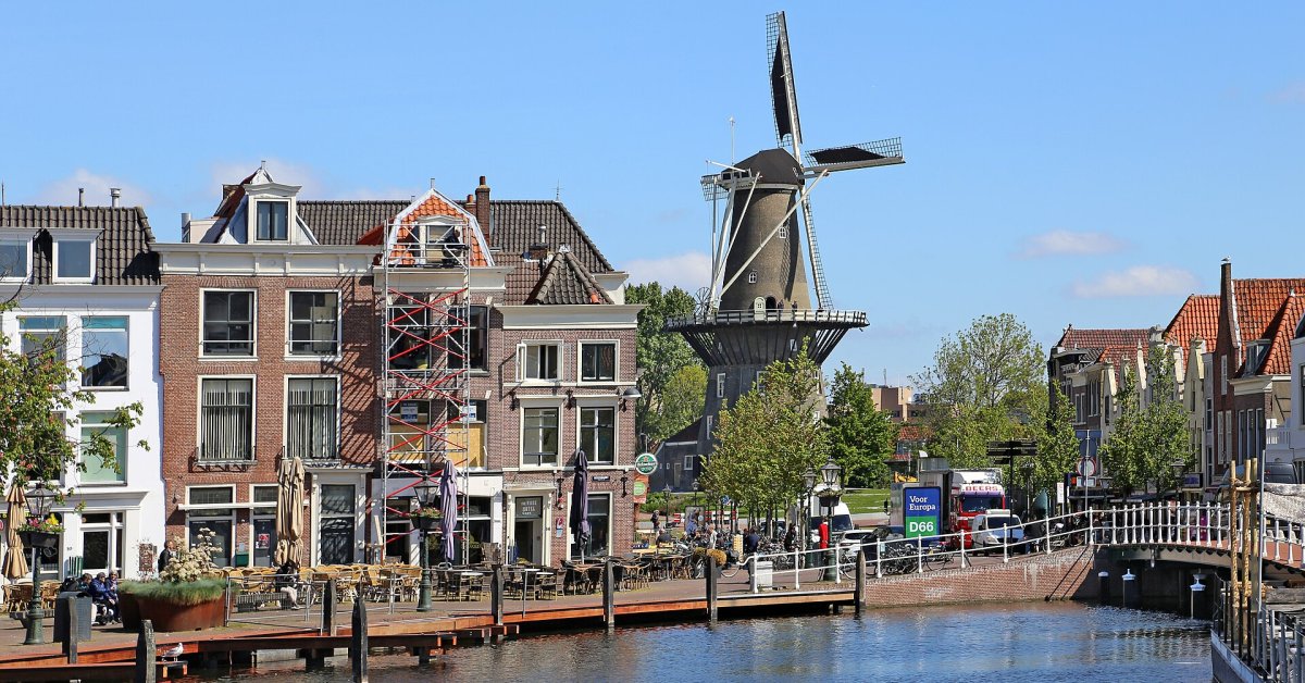 Gracht met historische huizen, een brug en een windmolen in Leiden